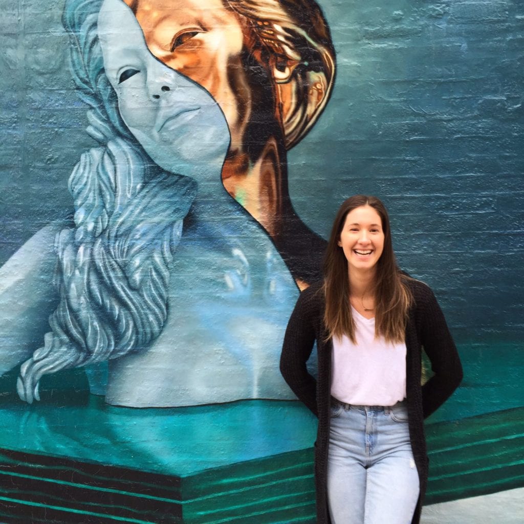 girl standing in front of painted wall mural