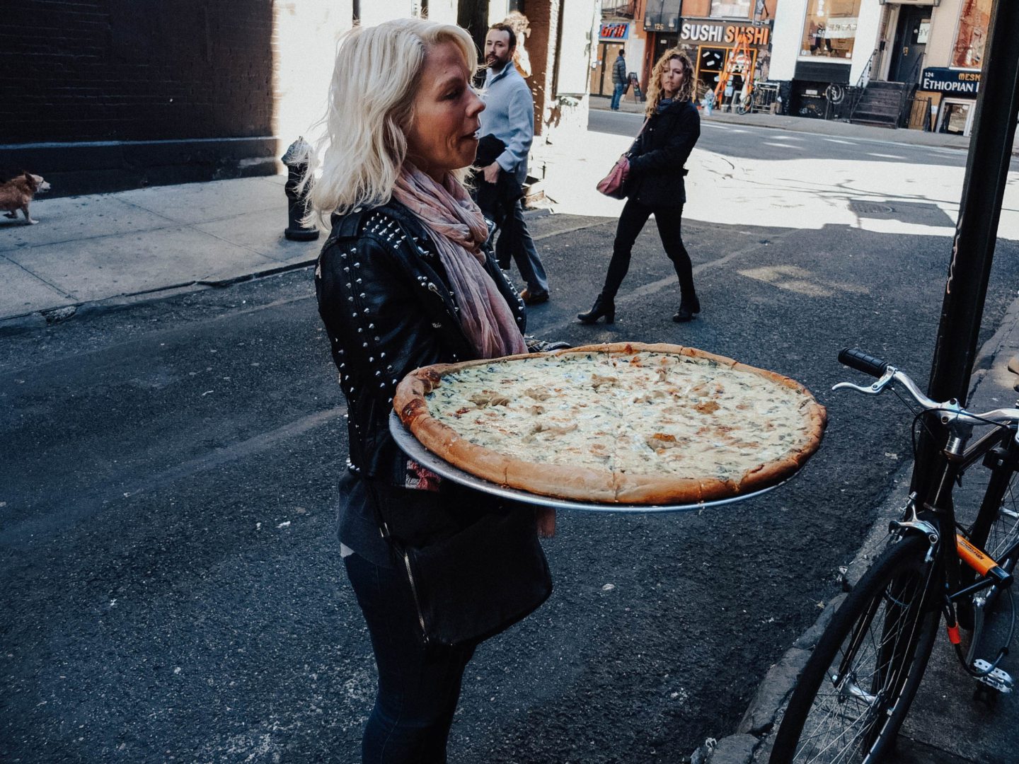 Lady holding a large pizza, New York City Food Tours