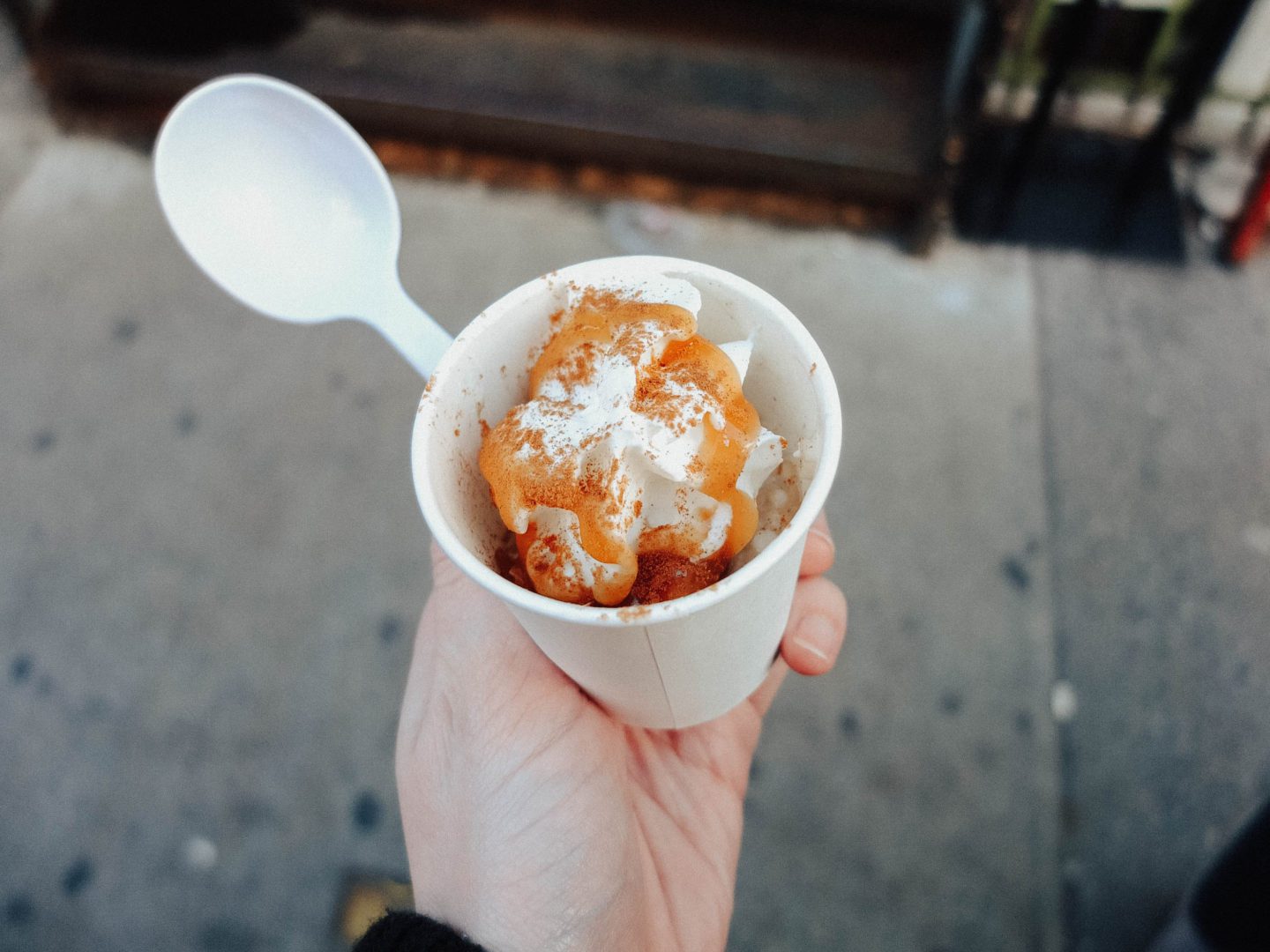 a hand holding a cup with oatmeal & a spoon