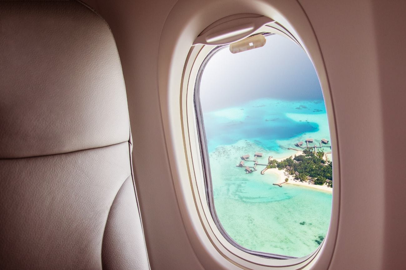 Plane window view of overwater bungalows, long haul flight