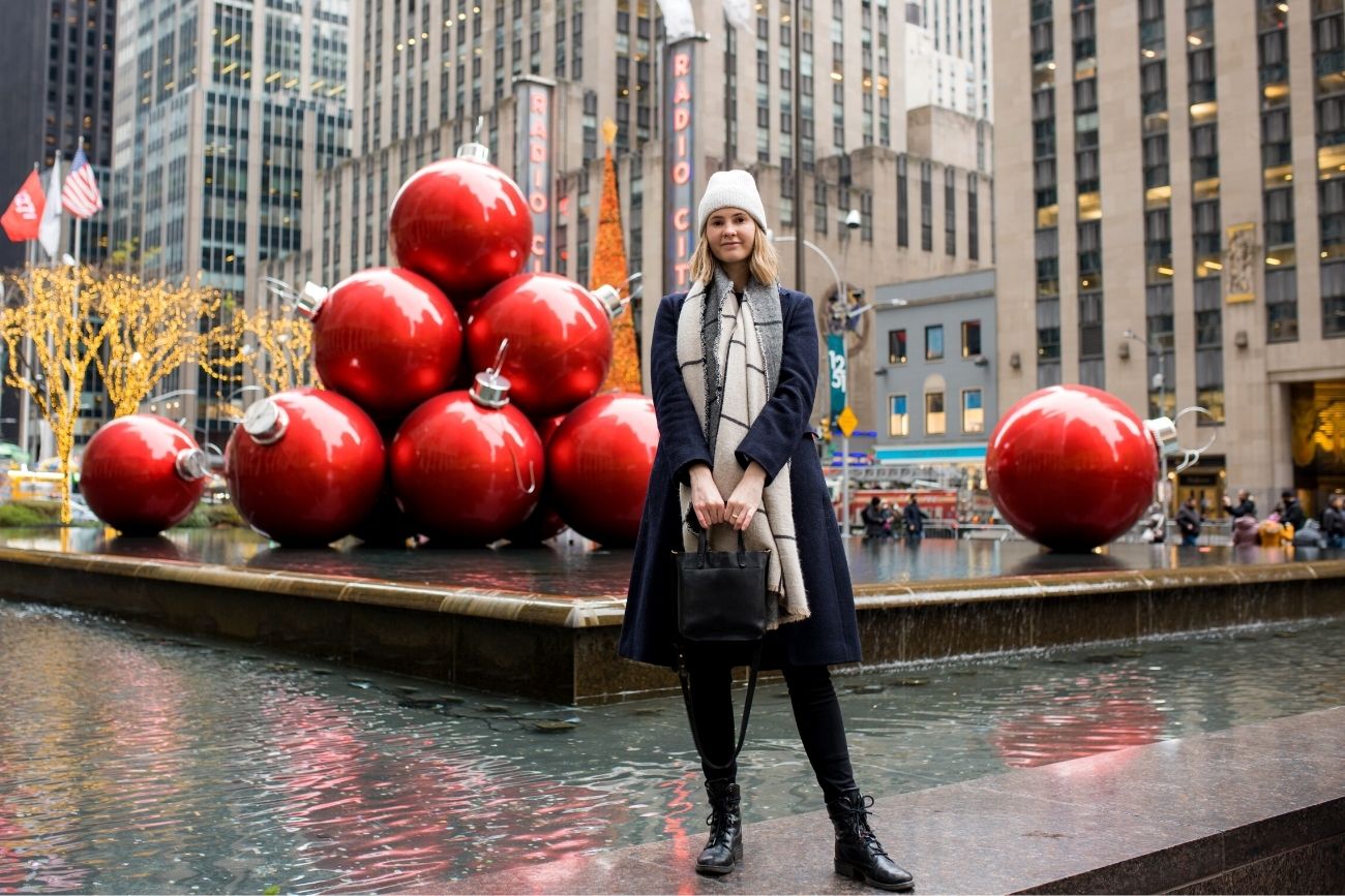 girl standing in front of water fountain display with Christmas baubles