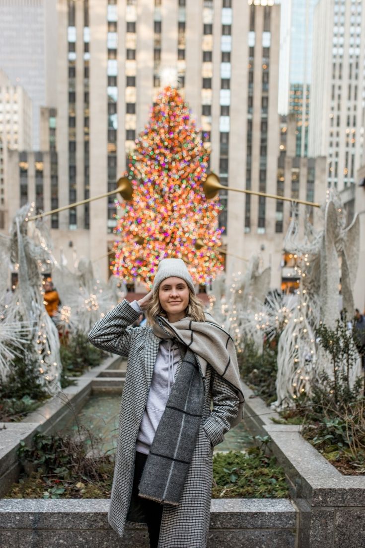 girl standing in front of a large Christmas tree