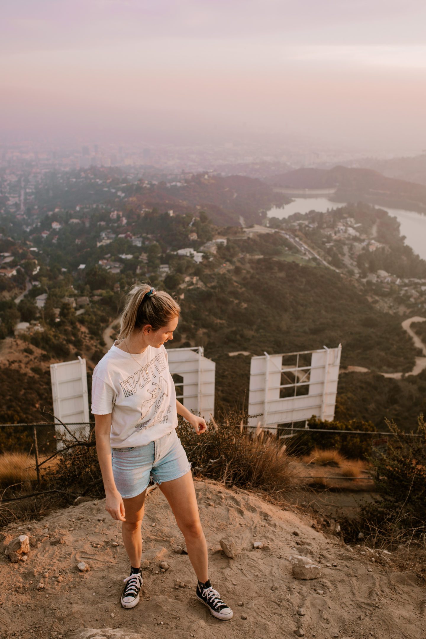Girl standing abobe the Hollywood Sign in Los Angeles, city view