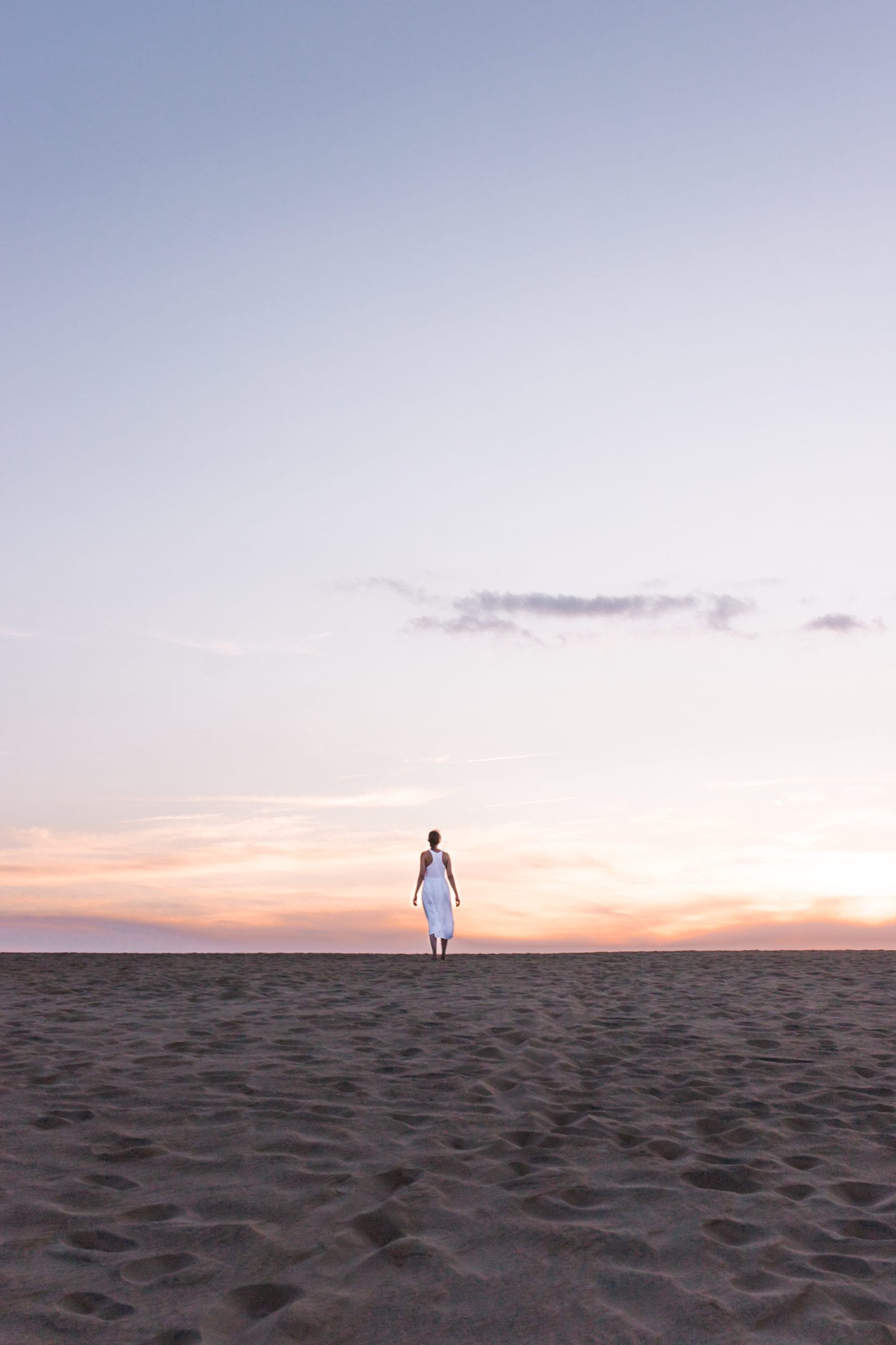 girl standing on a sand dune looking into the sunset, Outer Banks itinerary