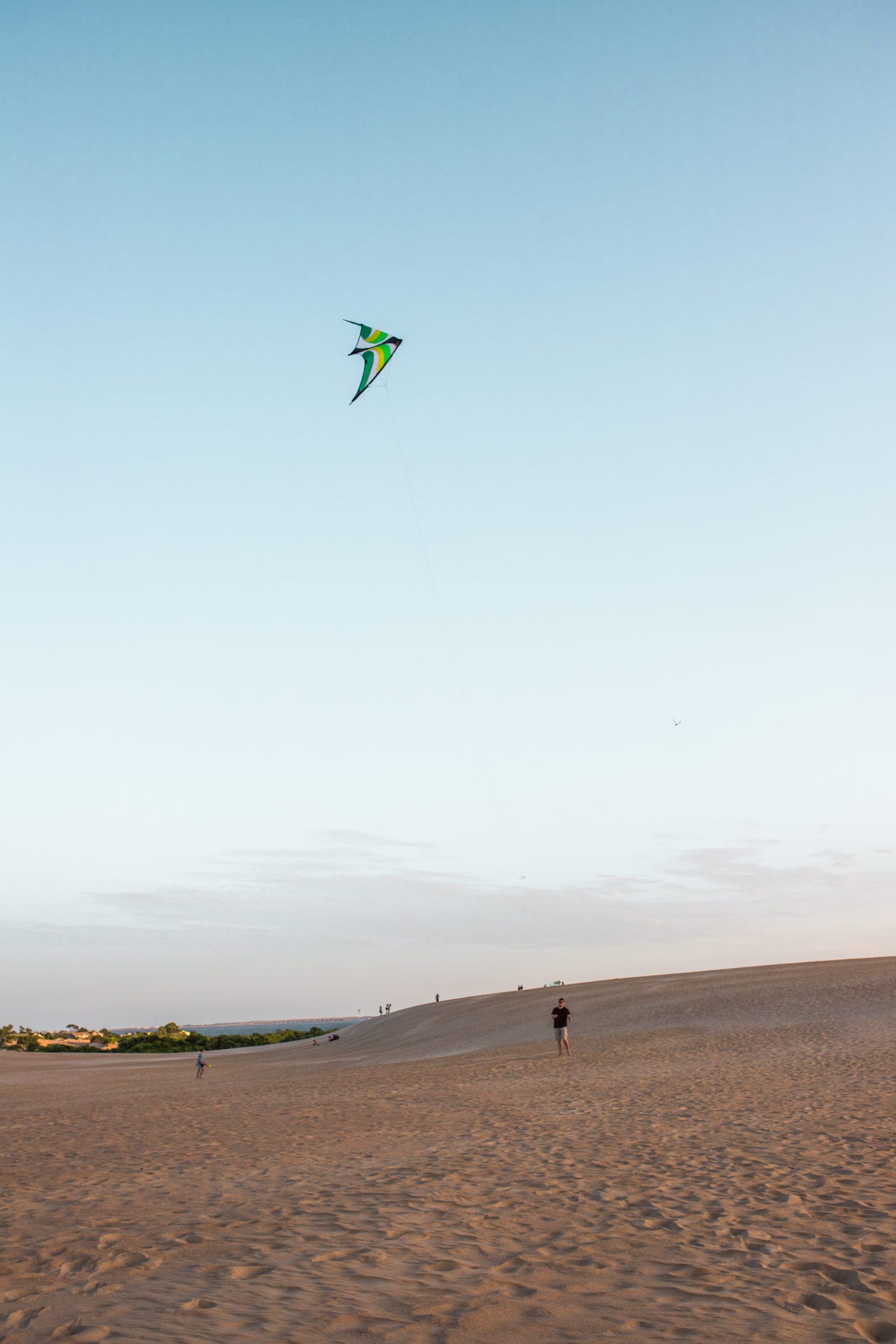 a man kite flying on the sand dunes