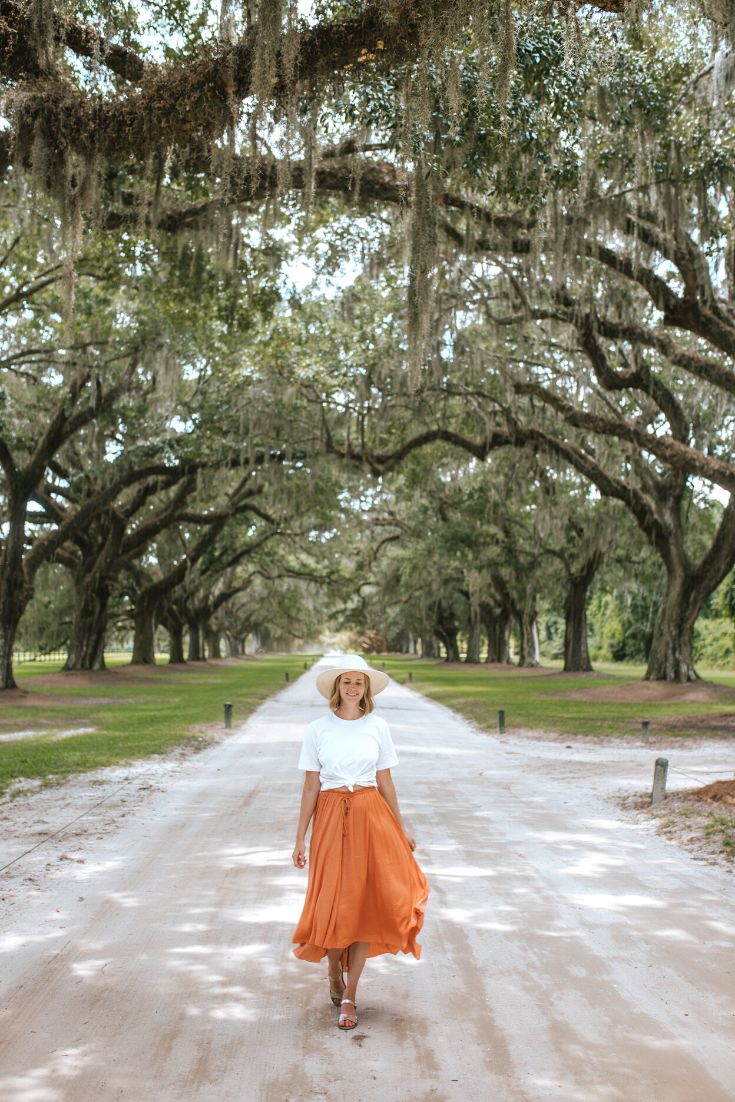 girl walking down a path through an alley of oak trees