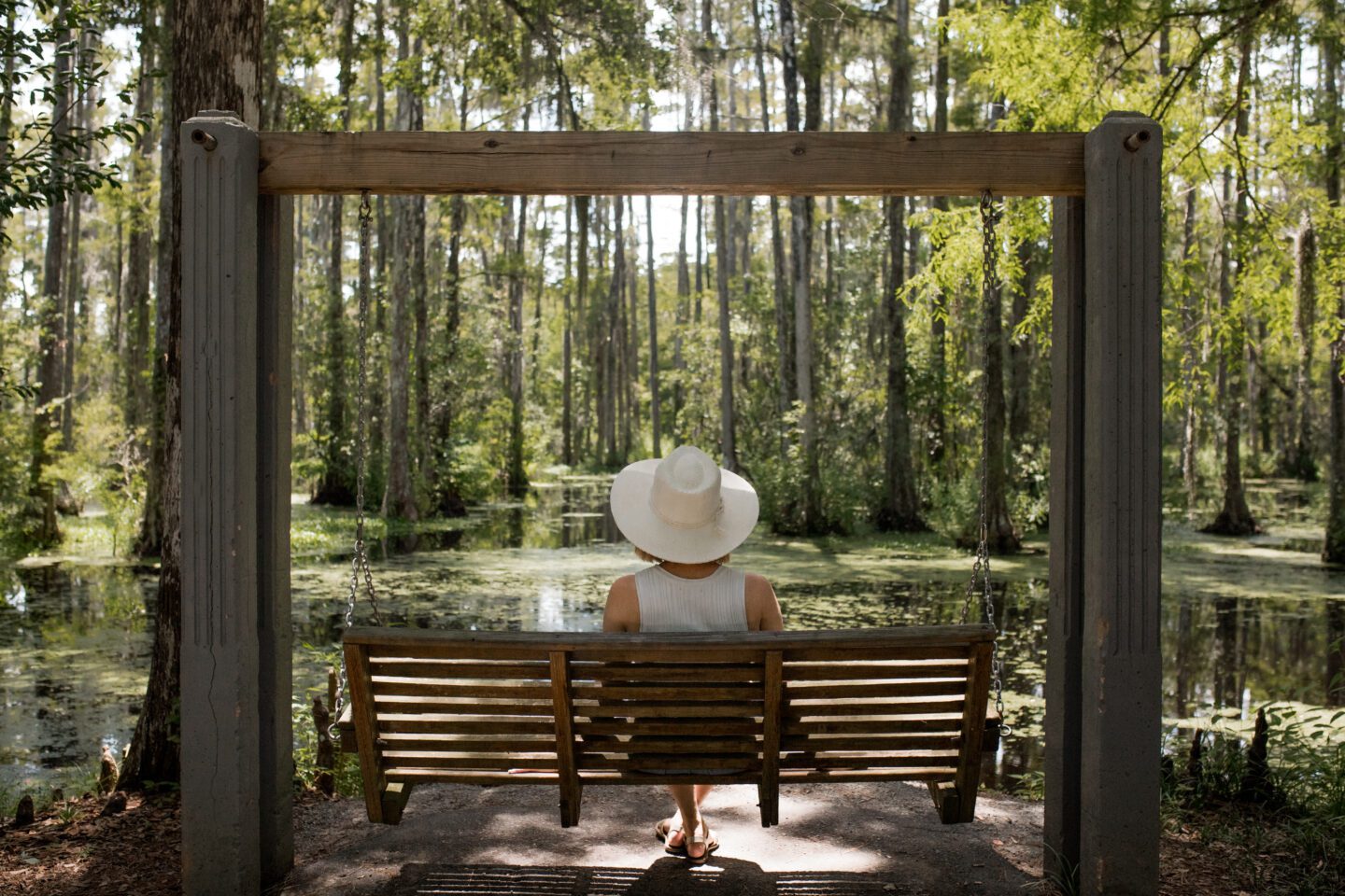 girl sitting on a swing in front of a swamp lake, charleston itinerary