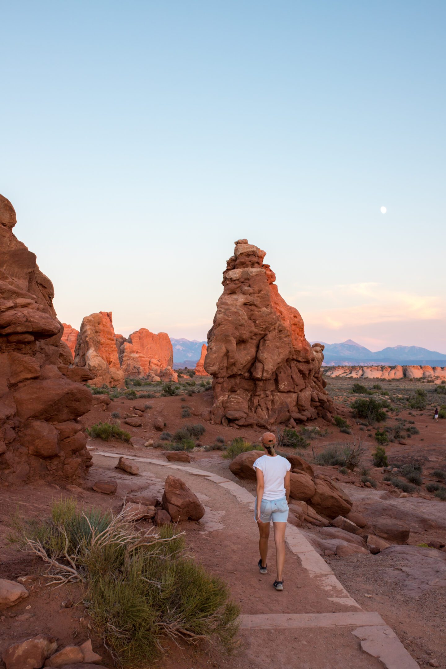 A girl walking on a sandy path between tall rock formations
