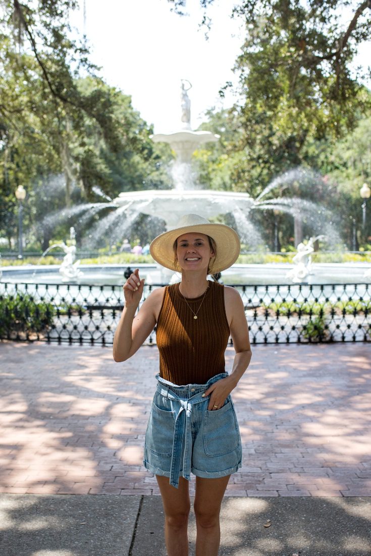 Girl in a hat standing in front of a water fountain