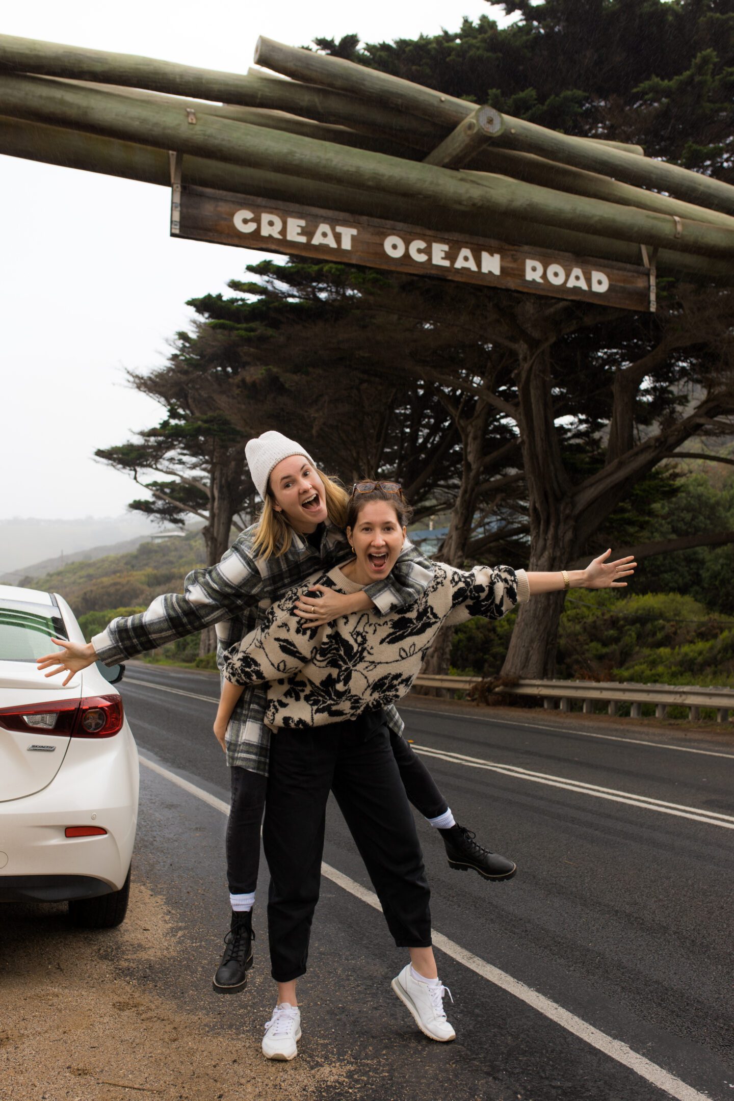 Two girls posing on the road under a wood sign, things to do in Warrnambool