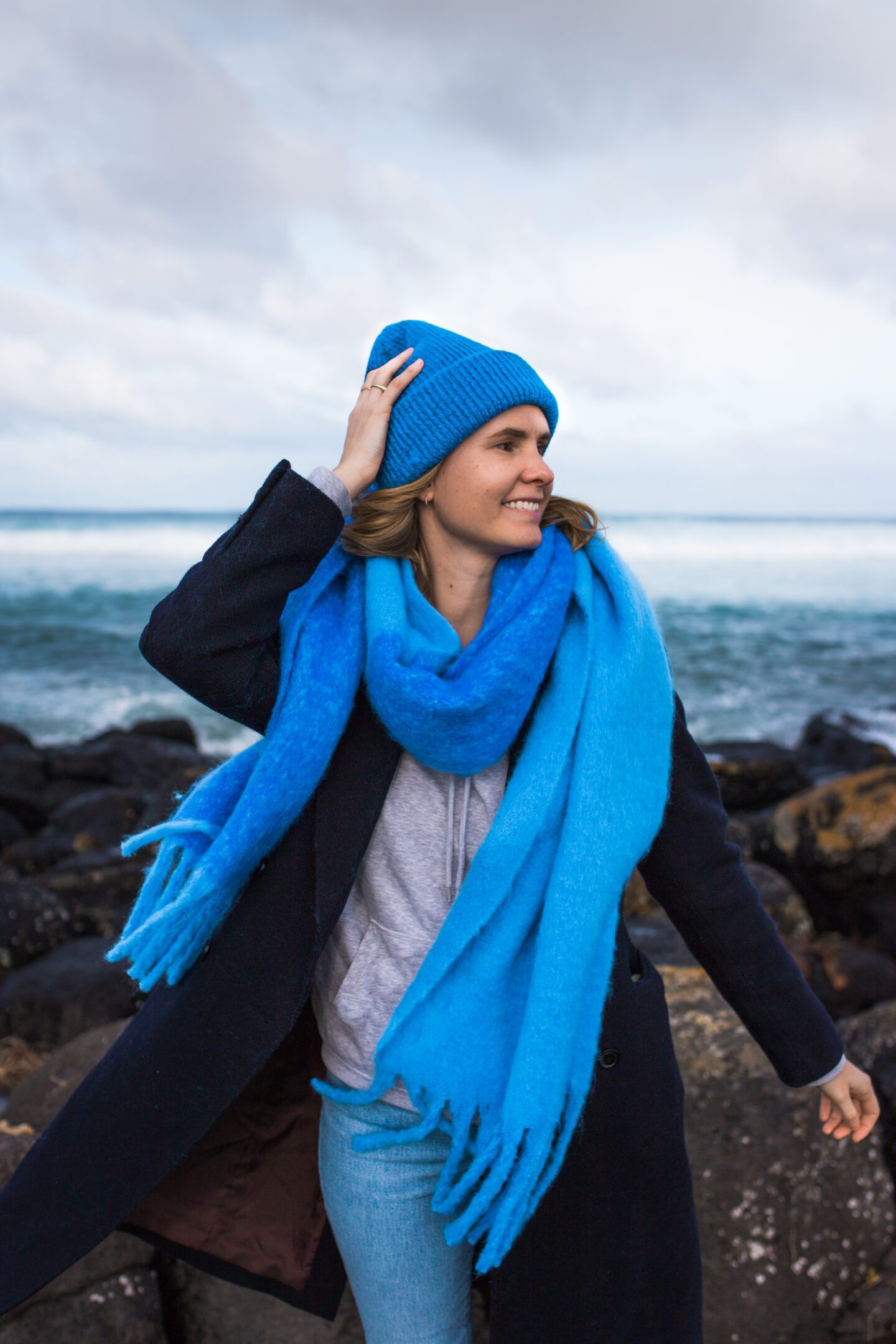 Portrait shot of a girl in a bright blue scarf and beanie on the beach