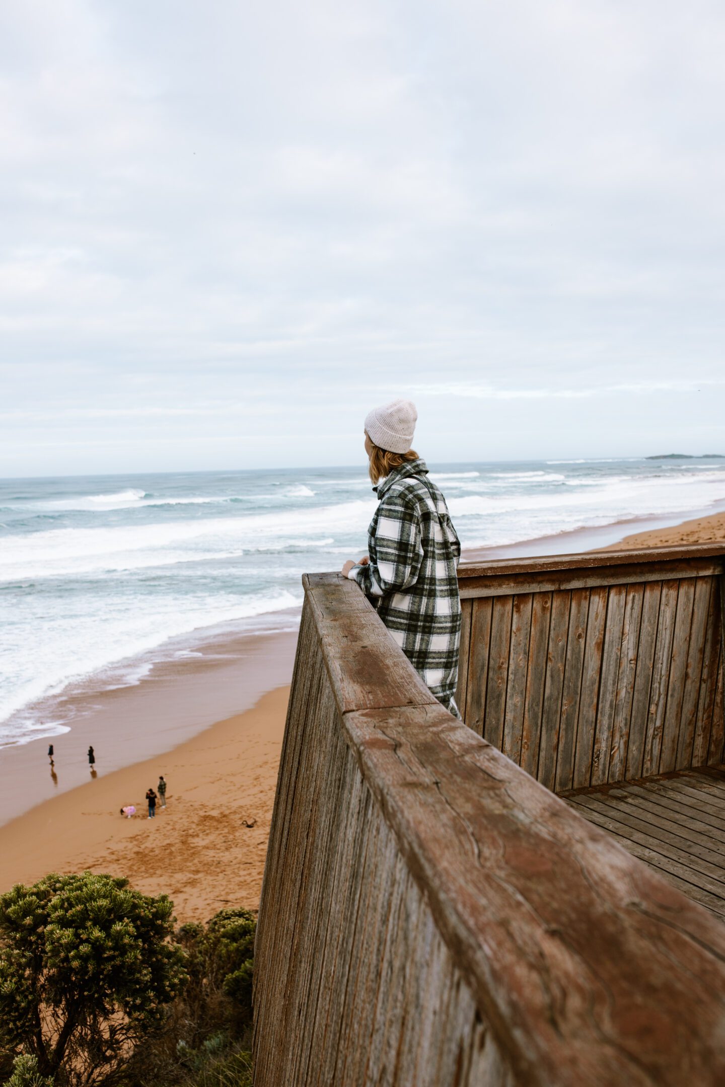 A girl looking out at the ocean from a wooden viewing platform, 