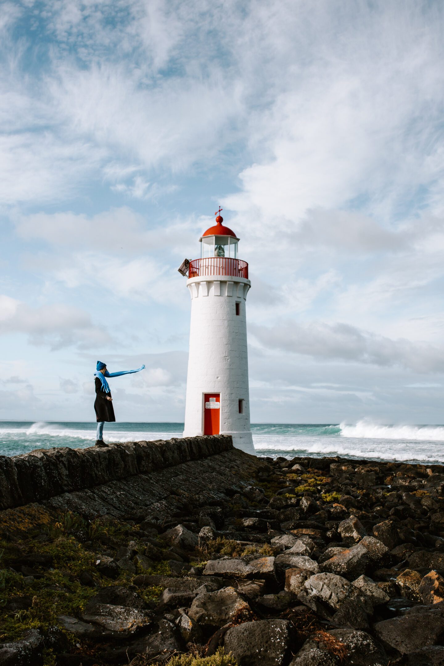 Girl standing next to a lighthouse with scarf blowing in the wind, things to do in Warrnambool