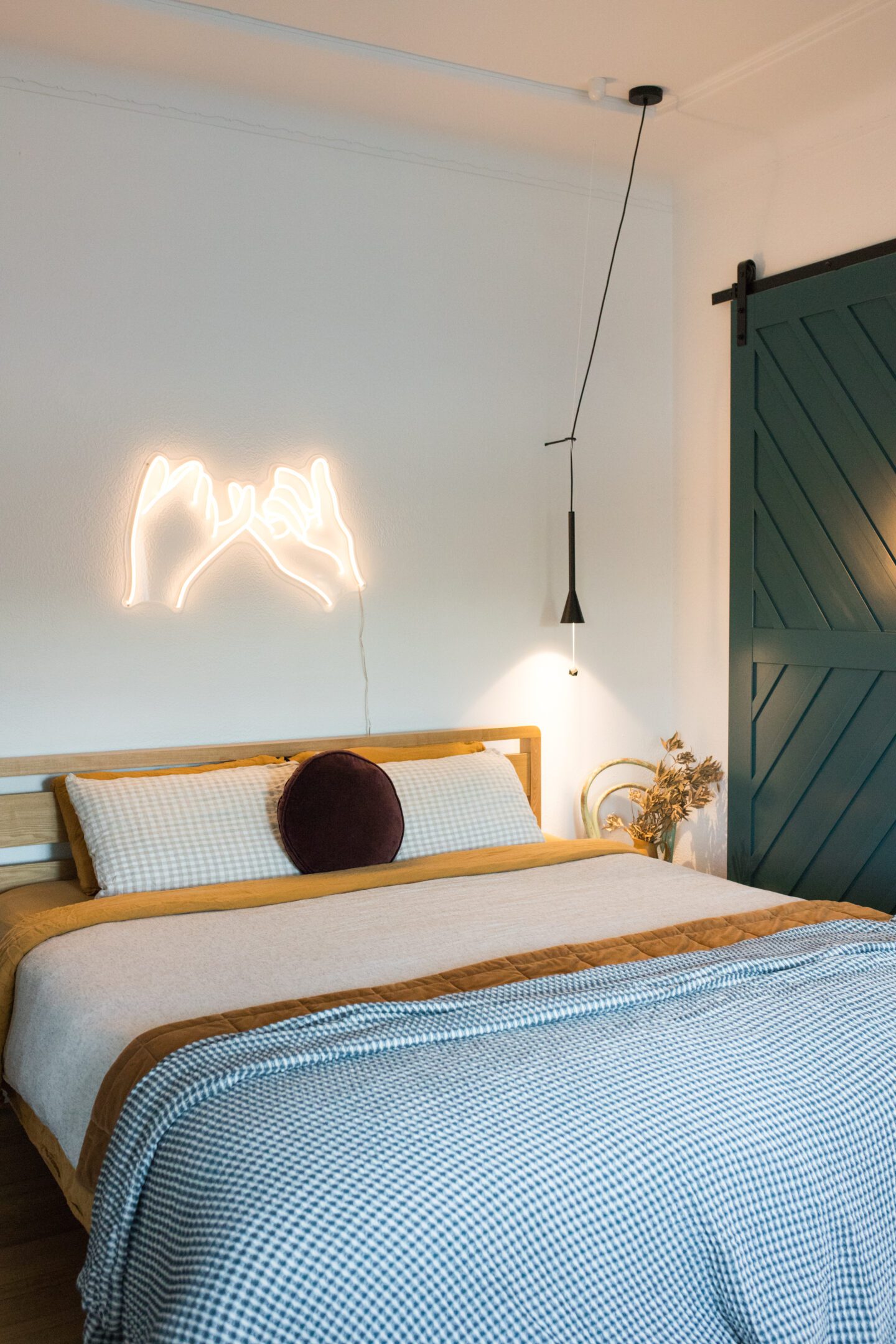 A king bed with a neon sign above the bead head